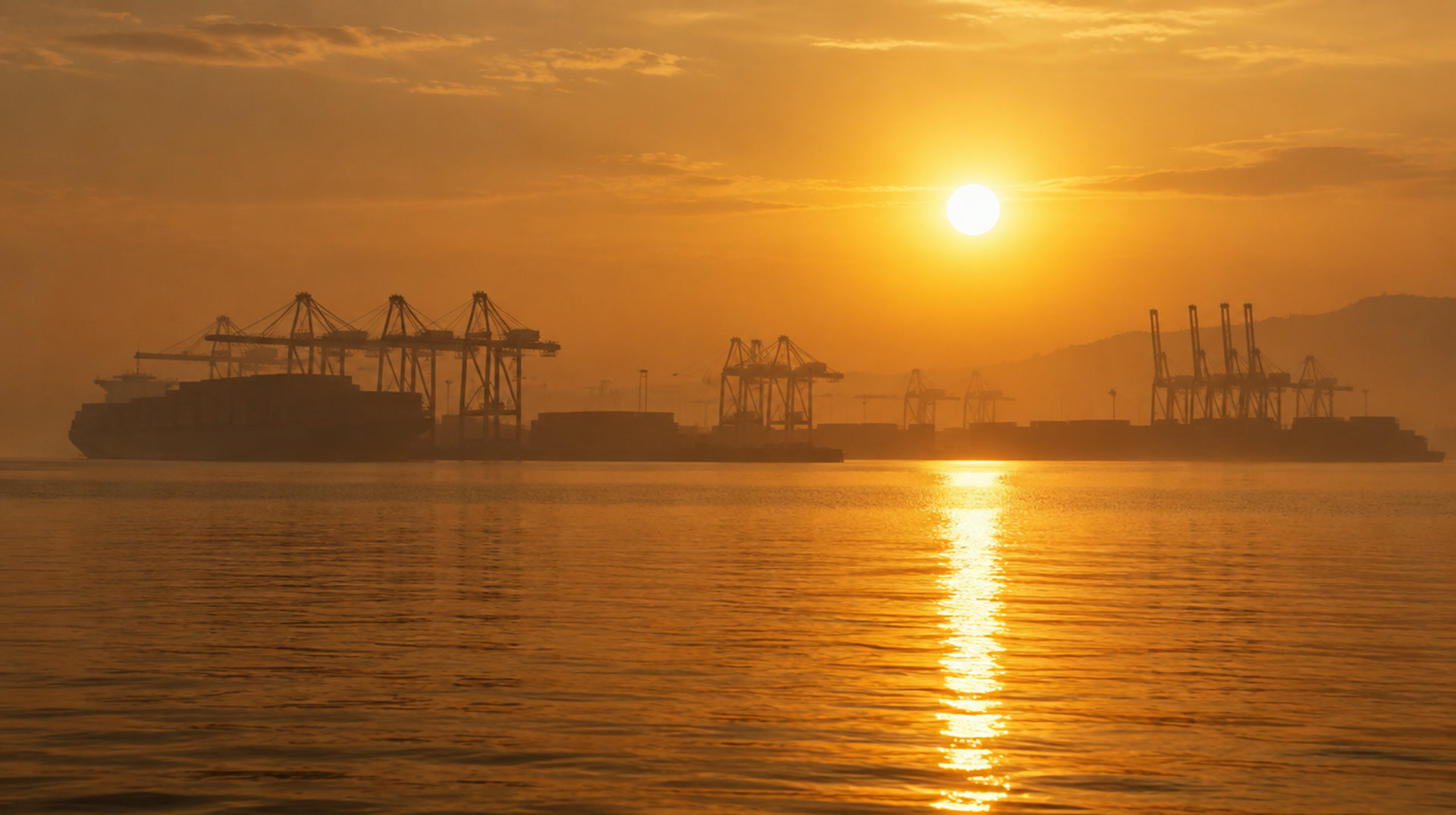 Illustrative image: a container port in silhouette at golden hour